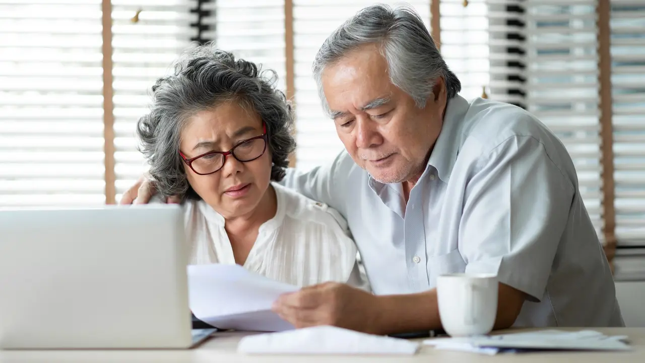 Senior Couple calculate their monthly expense or retirement savings strategy in stock photo.