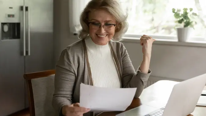 Happy adult retiree woman reading bank document stock photo