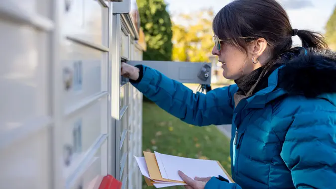 Woman Collecting Post at Home at the Mailbox in Autumn, Quebec, Canada stock photo