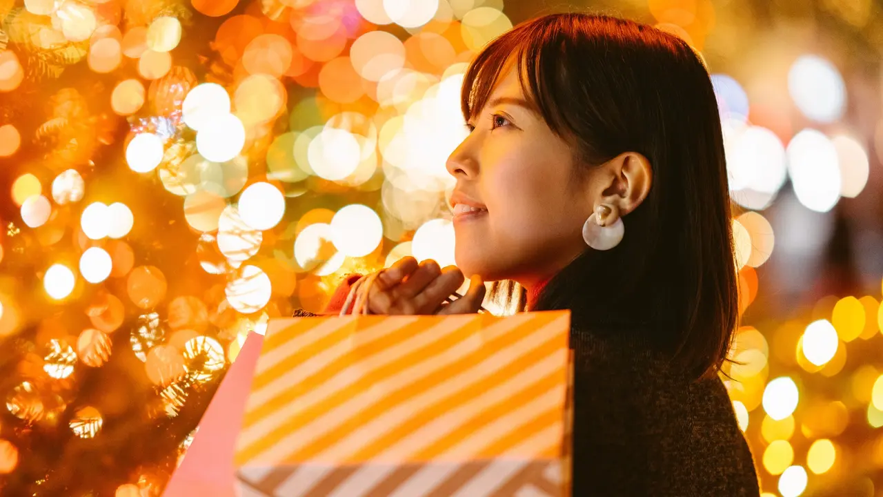 Portrait of young woman holding shopping bags at night stock photo