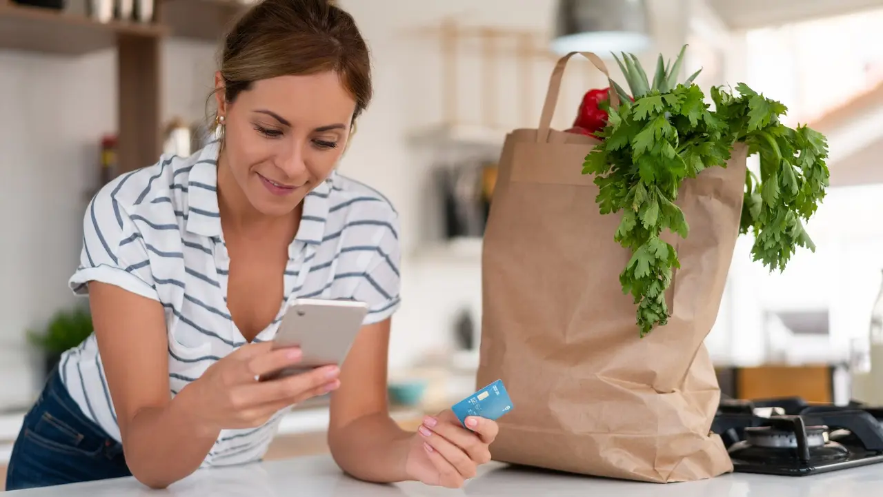 Woman at home paying online for a food delivery with a credit card stock photo