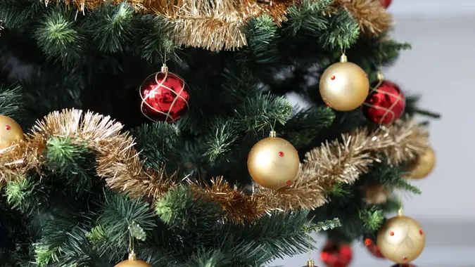 Artificial Christmas tree decorated with red-gold balls and tinsel.
