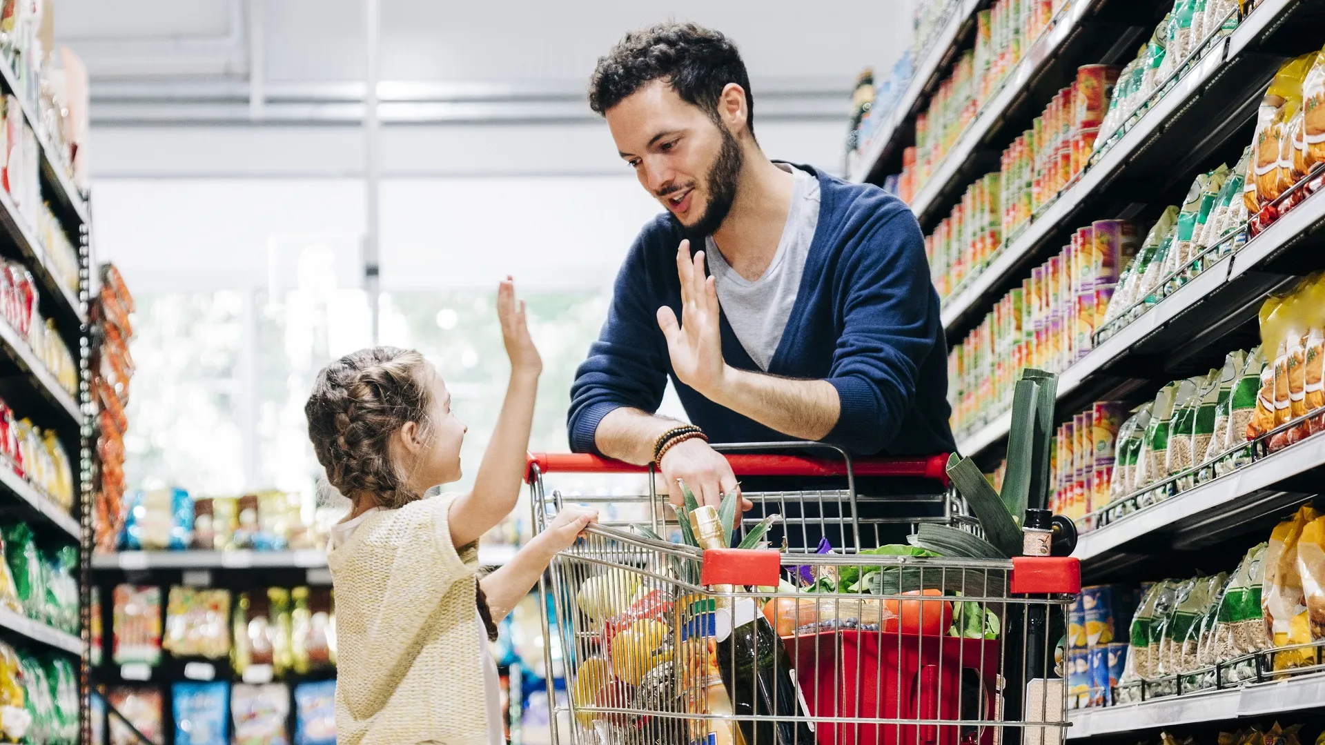Father giving high five to daughter in supermarket stock photo