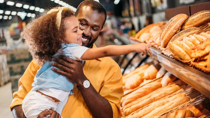 African american little child pointing by finger at pastry to father in supermarket stock photo