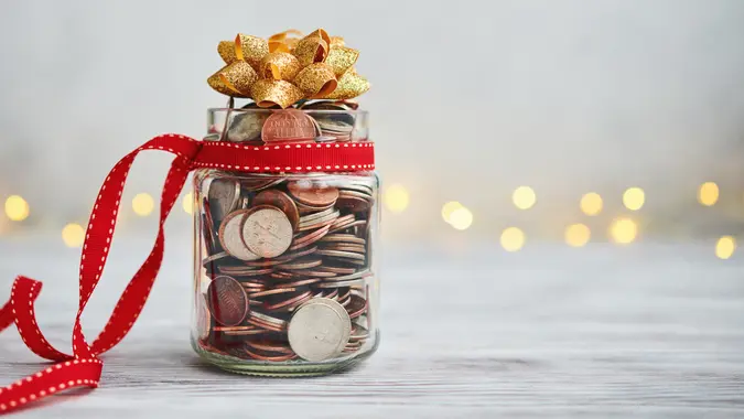 Holiday Savings Jar Filled with Coins and Christmas Ribbon and Bow.