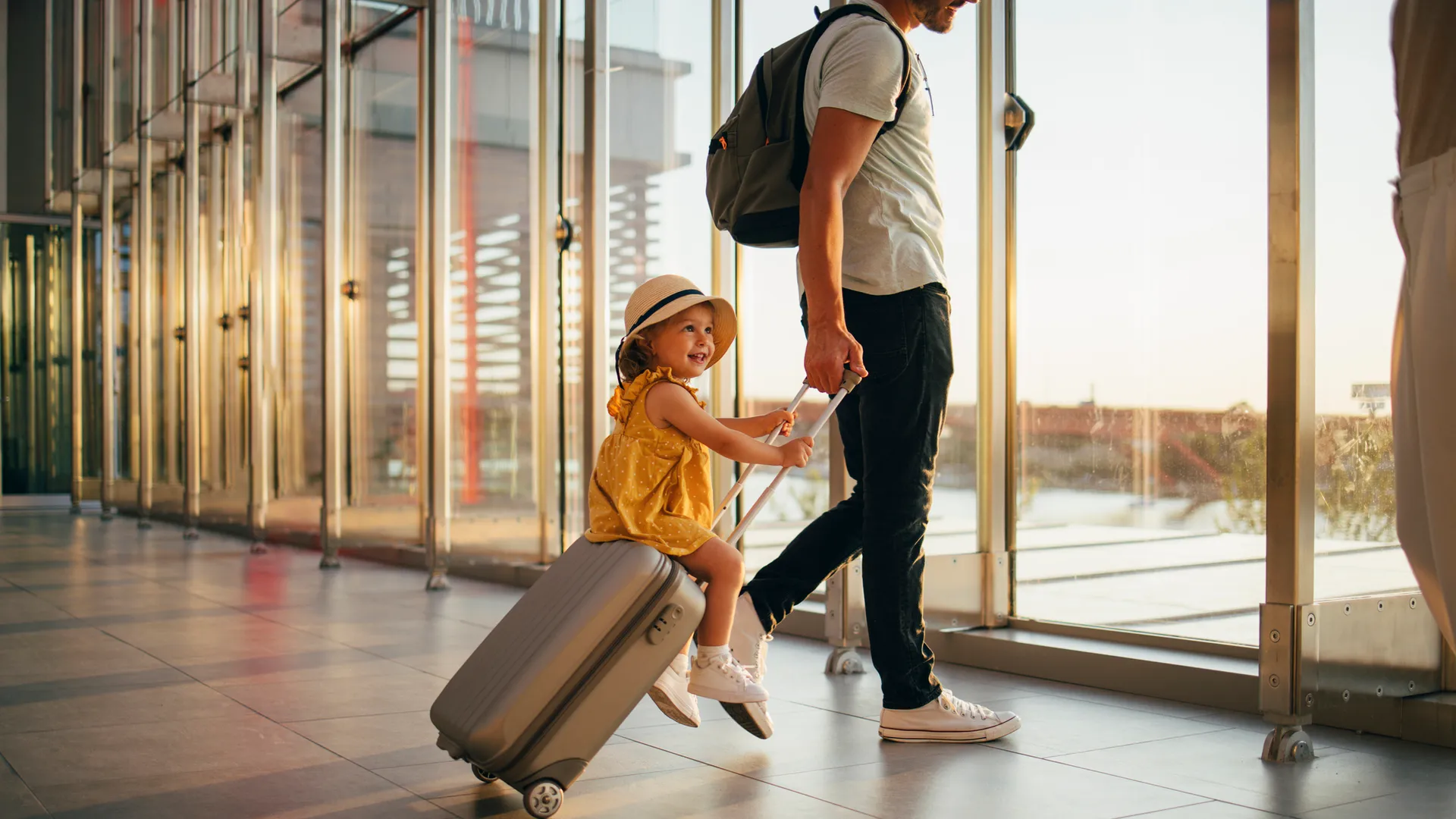 快乐的丈夫和匿名的妻子走的小女孩坐在机场的行李。