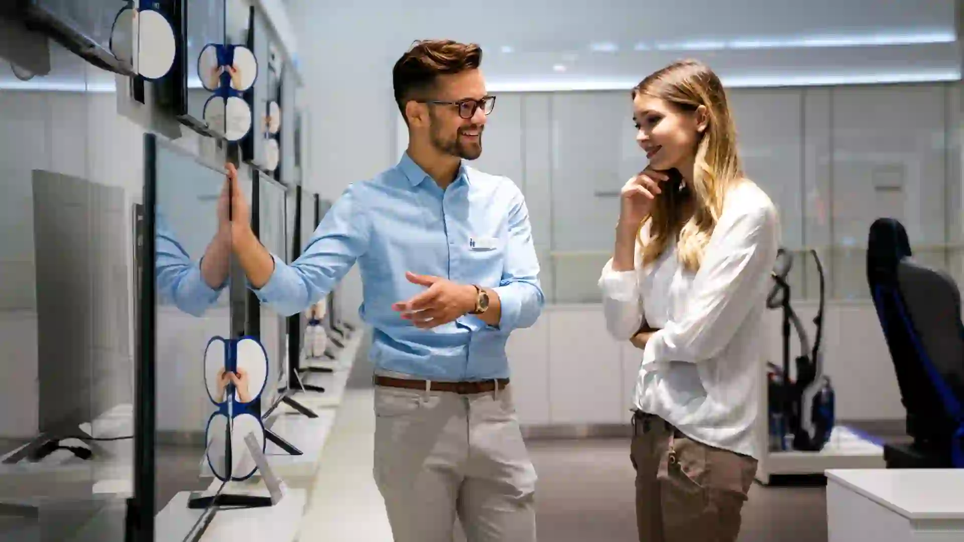 Portrait of salesman helping to woman to buy a new digital device in tech shop.
