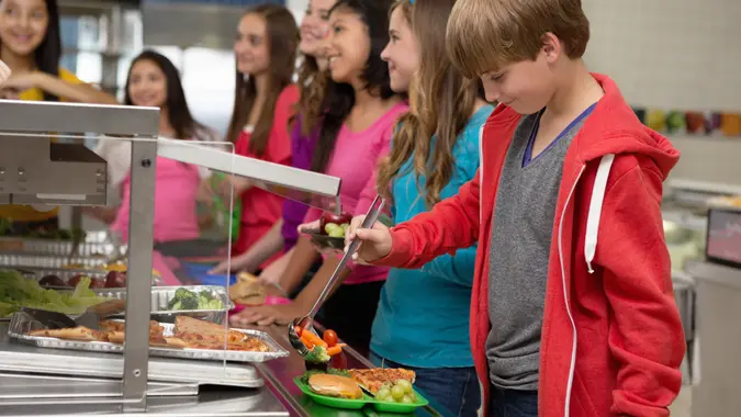 Middle school students choosing healthy food in cafeteria lunch line.