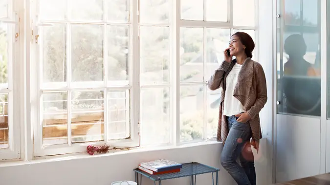 Cropped shot of a young woman using her cellphone in the kitchen.