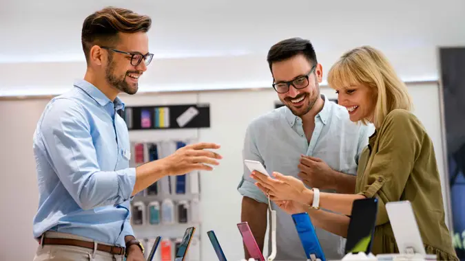 Portrait of salesman helping to couple to buy a new digital device in tech shop.