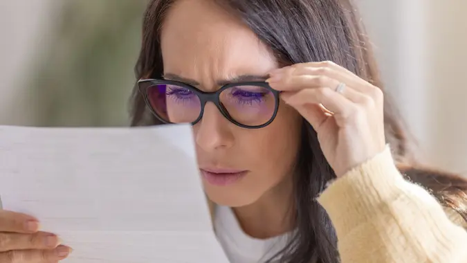 The woman has vision problems and reads the letter very close to her eyes and glasses. stock photo