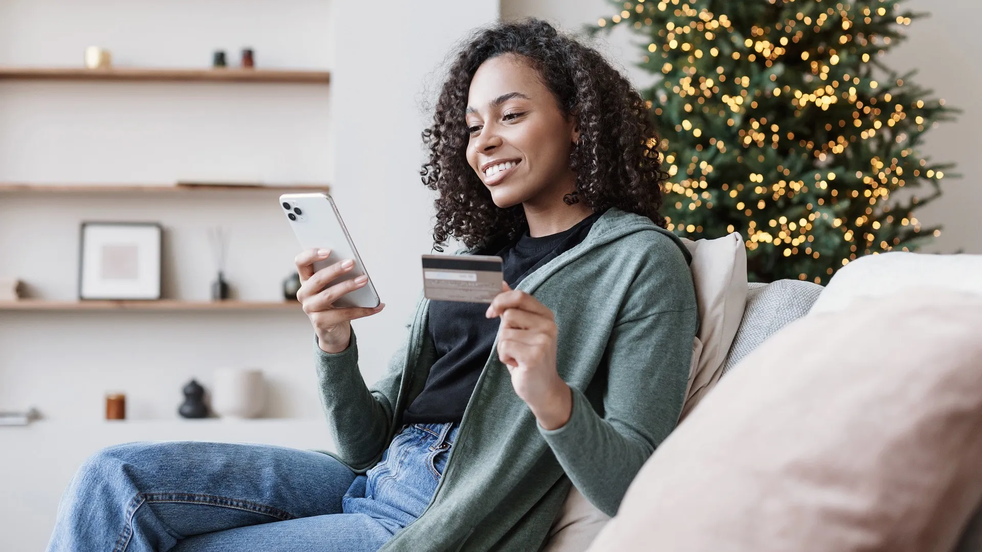 女人使用智能手机和信用卡订购圣诞礼物。网上购物在假期期间股票的照片
