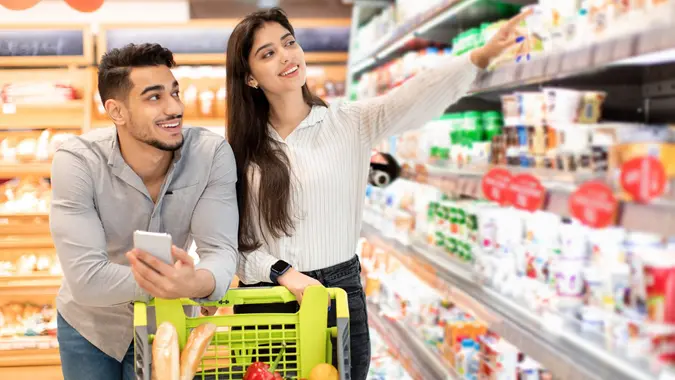Arabic Spouses Shopping Groceries Pointing Finger At Shelf In Supermarket stock photo