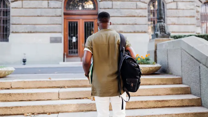 Rear view of a young African American male student going to a university stock photo