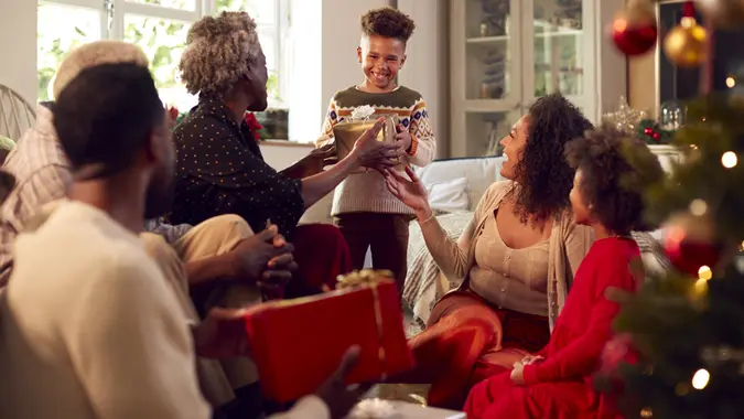 Multi-Generation Family Exchanging And Opening Gifts Around Christmas Tree At Home stock photo