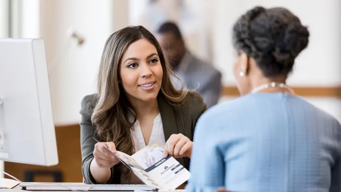 A cheerful female banker explains the different types of banking accounts to a new customer.