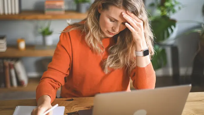 Mature adult woman working at home (laptop, document, negative emotions) stock photo