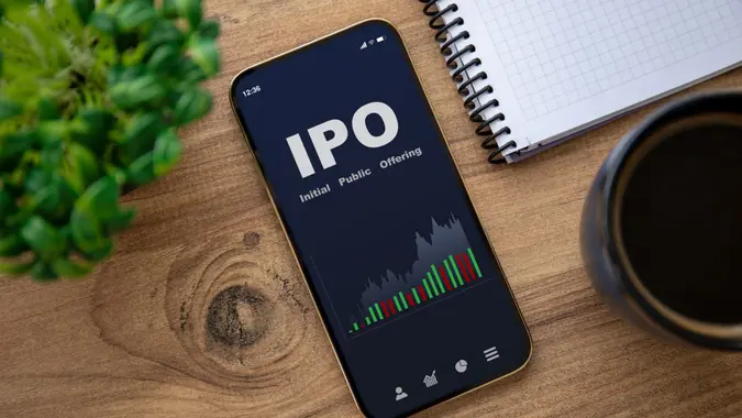 golden phone with IPO stocks purchase app on the screen on wooden table in office.