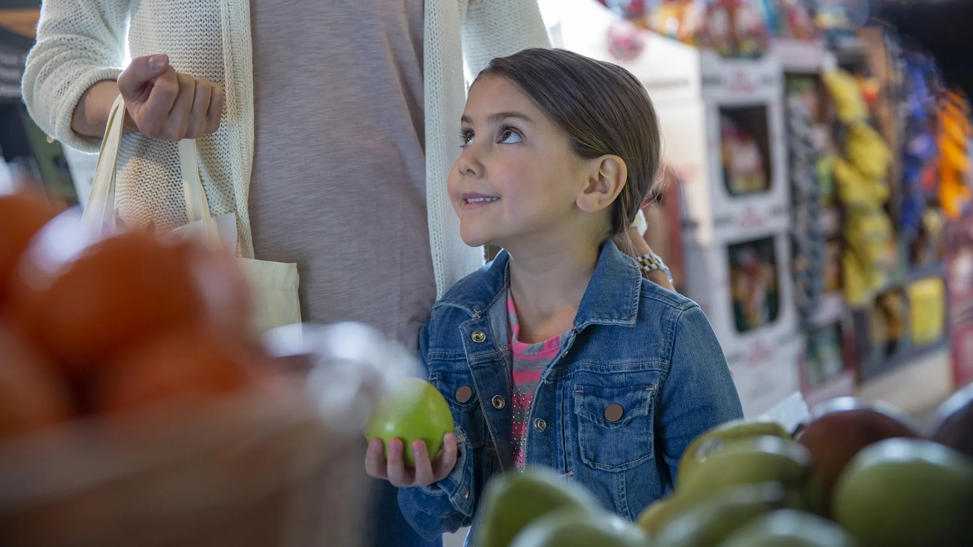 Smiling mother and daughter picking out produce in grocery store stock photo