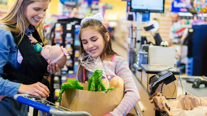 Mother shopping in grocery store with young daughters stock photo