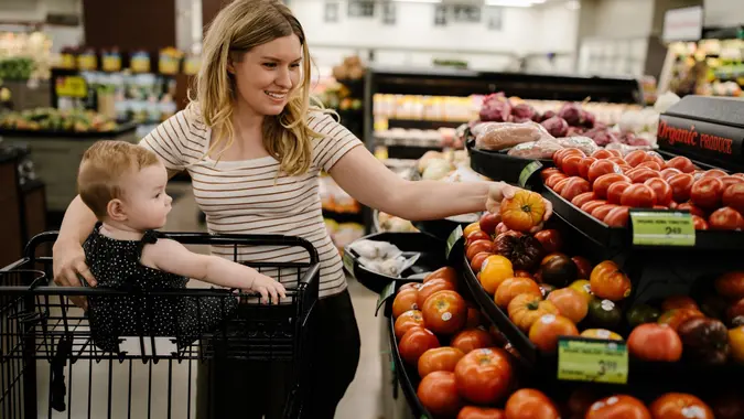 Mother and her toddler daughter buying organic tomatoes at the grocery store stock photo