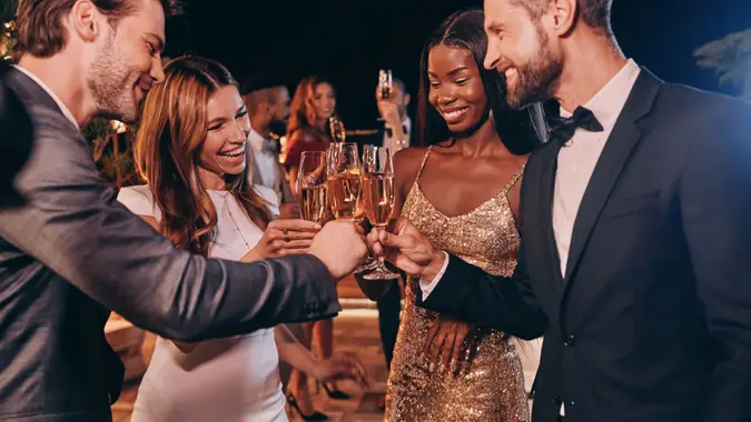 Group of people in formalwear toasting with champagne and smiling while spending time on luxury party.