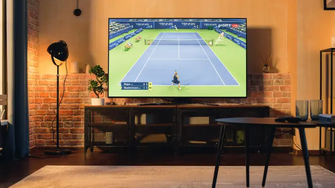 Stylish Loft Apartment Interior with Tennis Game Playing on Flat Screen Television.
