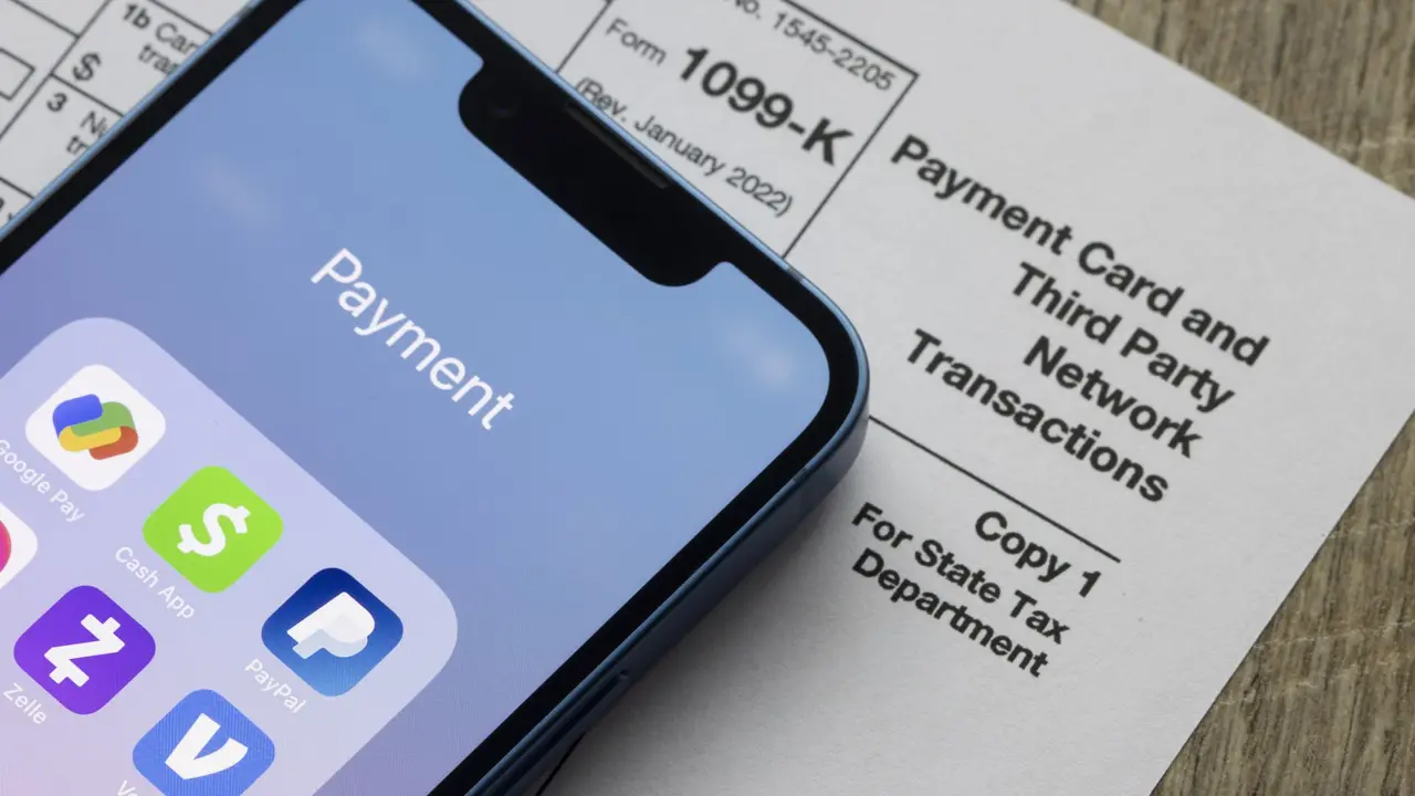Smartphone with payment apps next to a 1099-K tax form for third-party transactions.