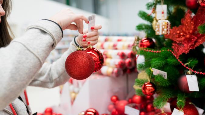 Close up of woman hands choosing and shopping Xmas decorations on Christmas tree in the market. Preparing and decorating the home before the holiday. stock photo