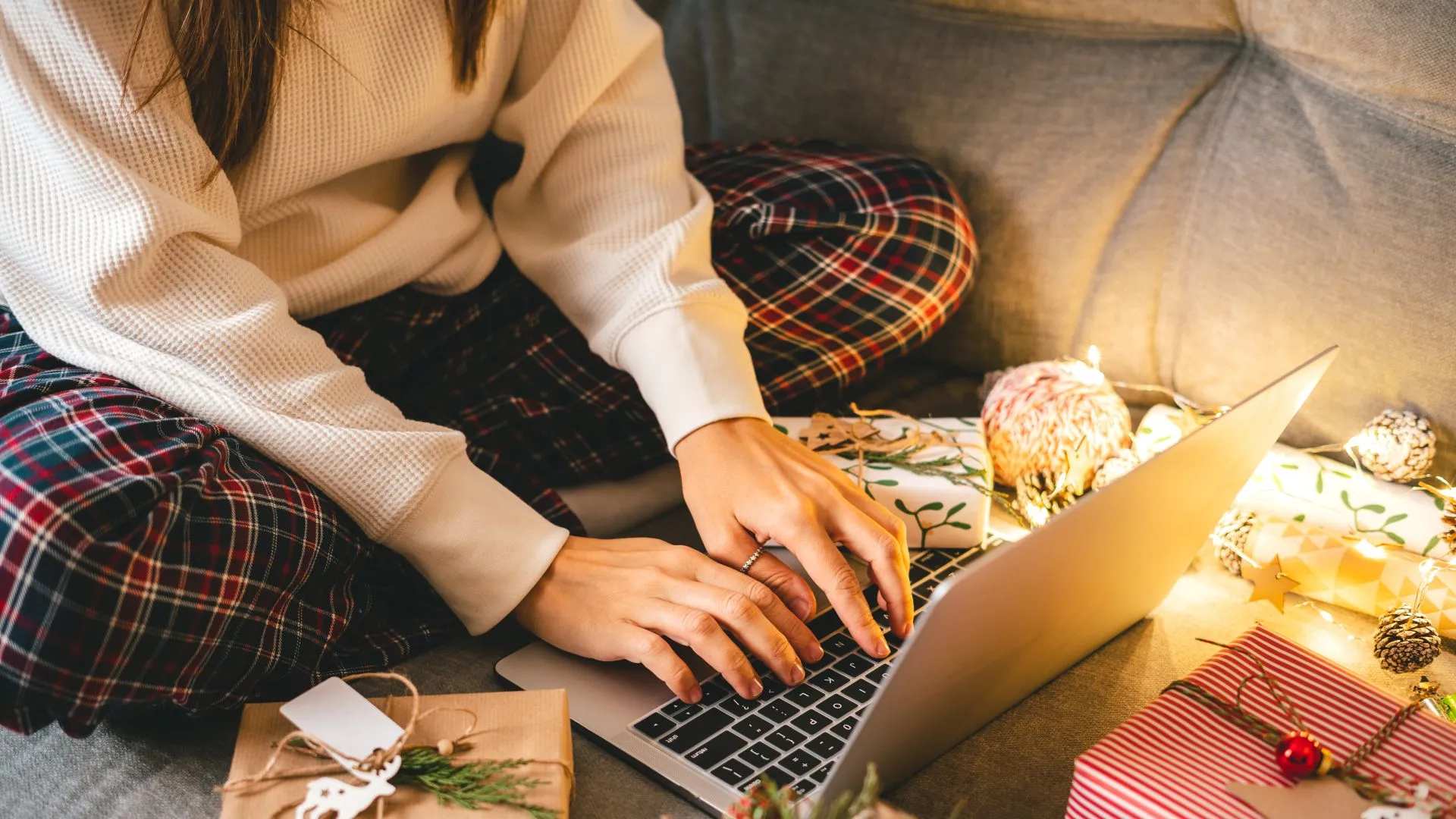 Close up of woman hands with gifts, typing at laptop.
