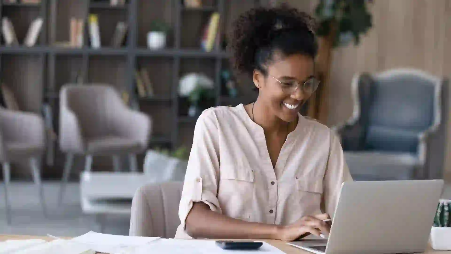 Happy millennial African American woman manage household budget calculate expenses expenditures on machine.