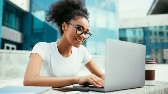 A young, happy woman works on her computer.