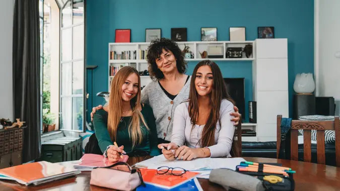Portrait of a mother with her daughter and a friend while they are doing homework at home.