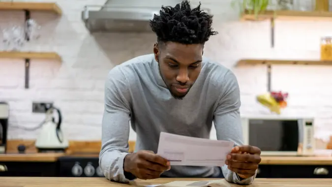 Portrait of a black man at home reading the mail - lifestyle concepts.