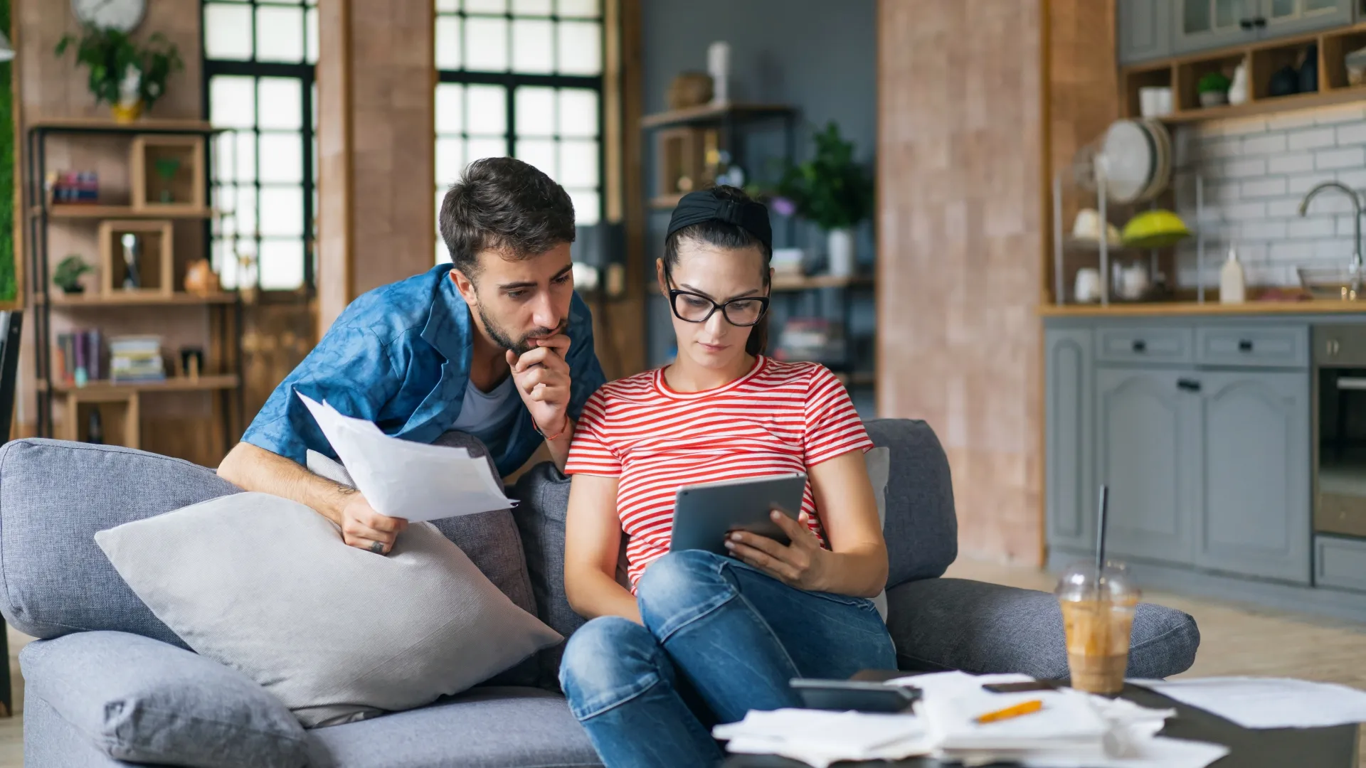 Couple calculating bills at home using laptop and calculator.