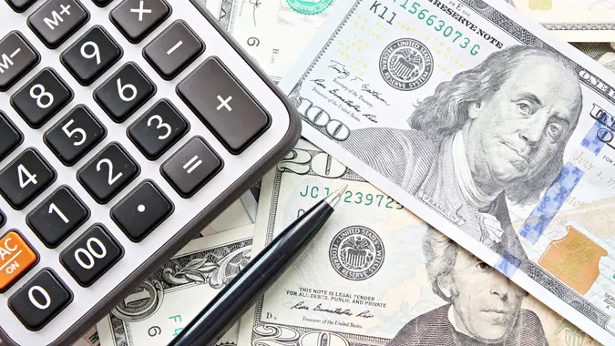 Business, finance, investment, accounting, taxes or money exchange concept : Top view or flat lay of calculator and pen on American Dollars cash money.