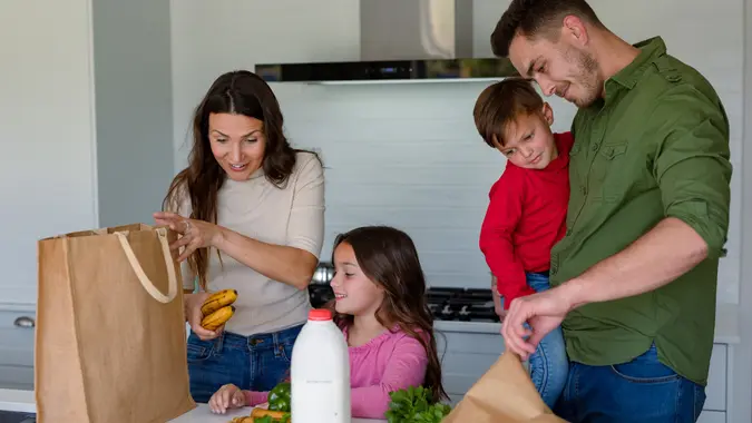 Happy caucasian family unpacking groceries together in kitchen stock photo