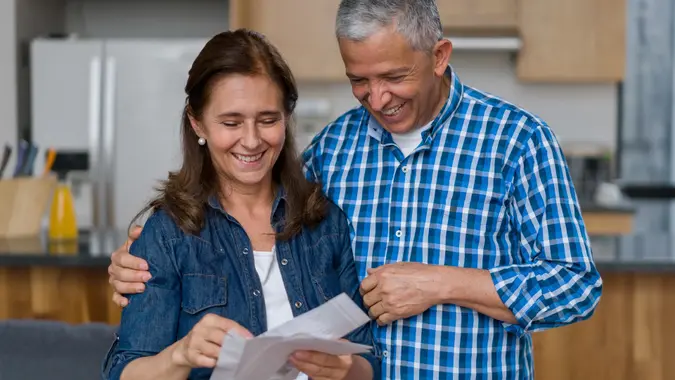 Happy adult couple at home checking a letter in the mail stock photo