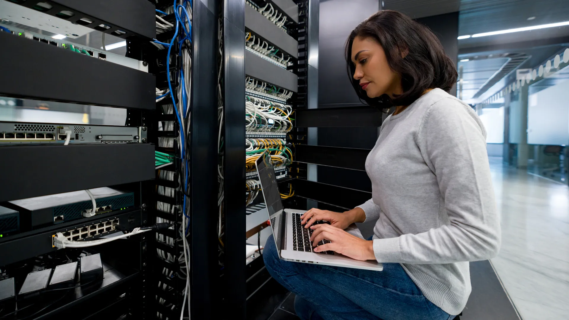 Female IT support technician fixing a network server at an office - technology concepts.