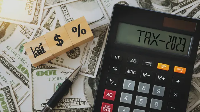 the word tax on the calculator  and icons on wooden blocks  Business and tax concept.