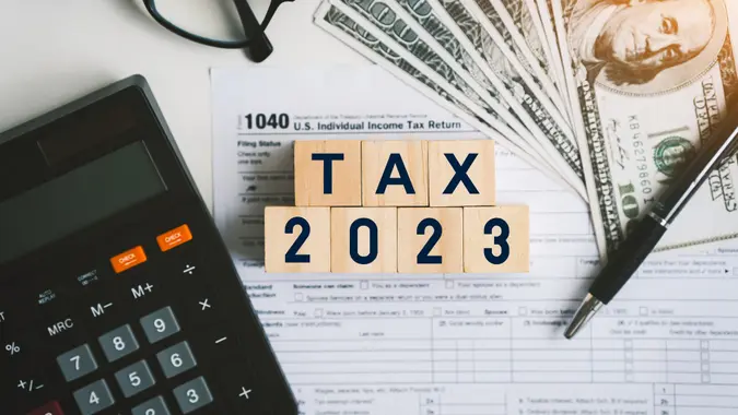 Tax text in wooden cubes and tax or vat form documents to complete Individual income tax return form for payment to Government.