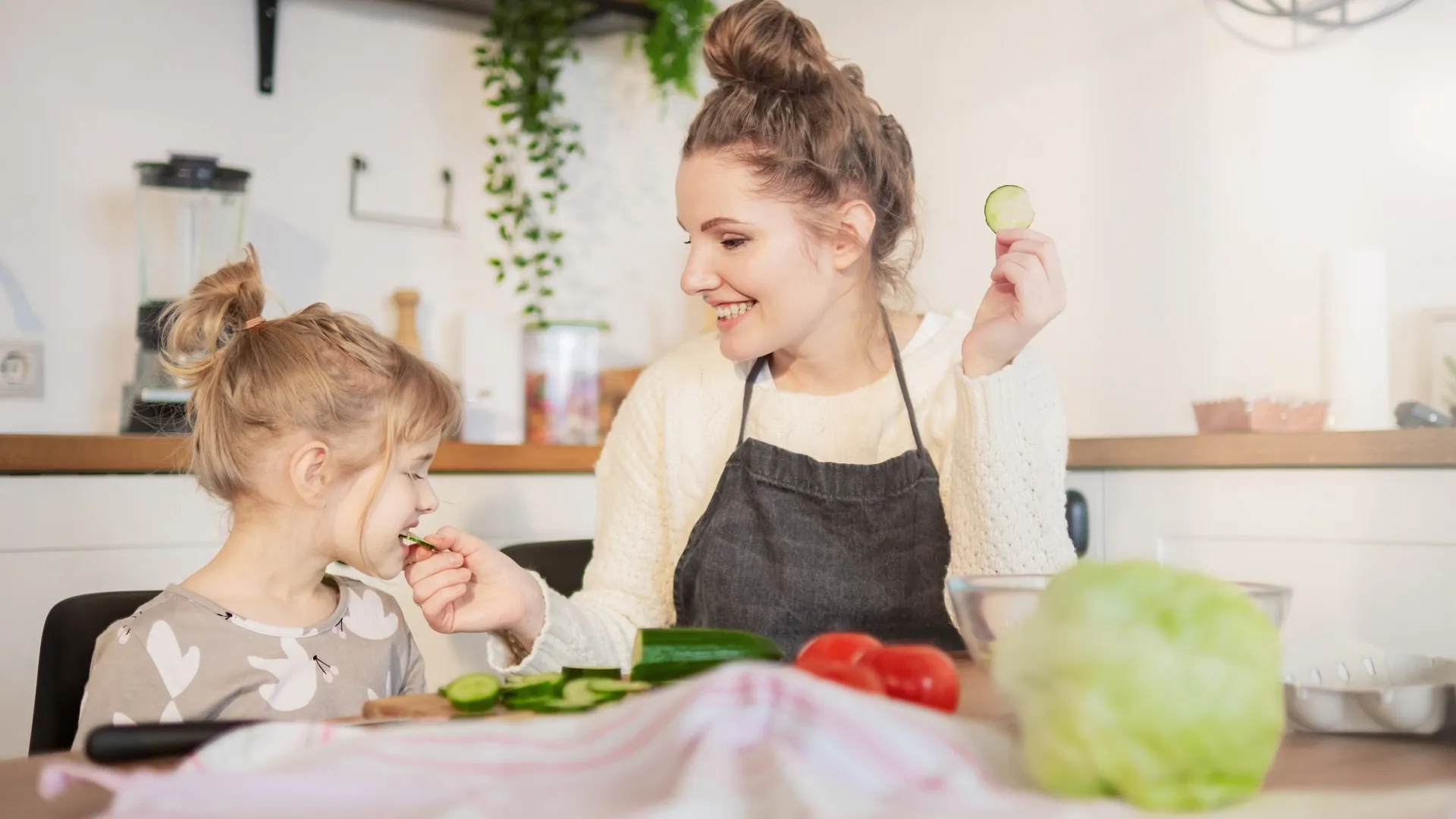 Caring young mother and little kid girl daughter cooking salad at home kitchen together for healthy family eating stock photo