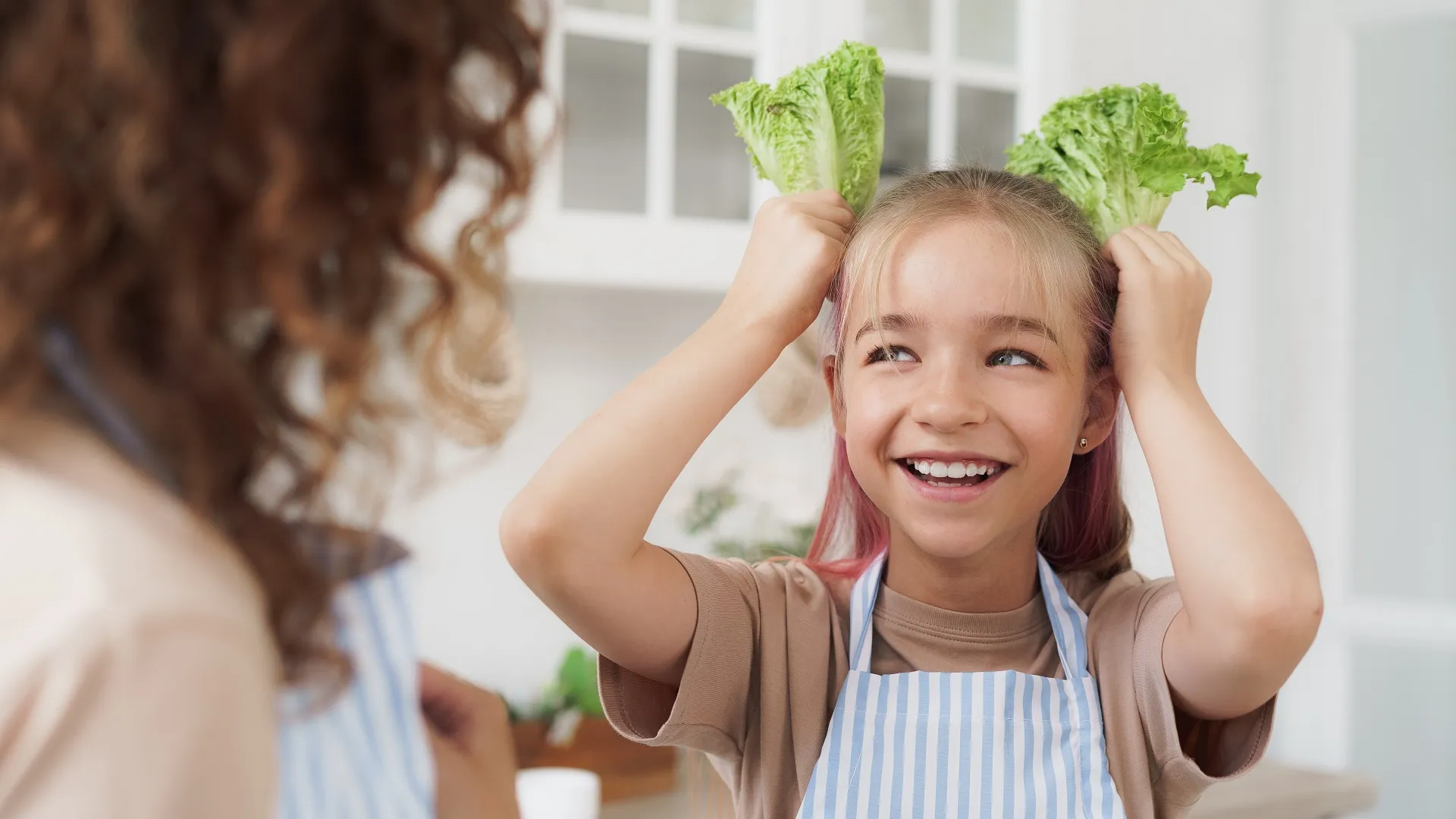Mother and daughter playing and having fun with vegetables in kitchen stock photo