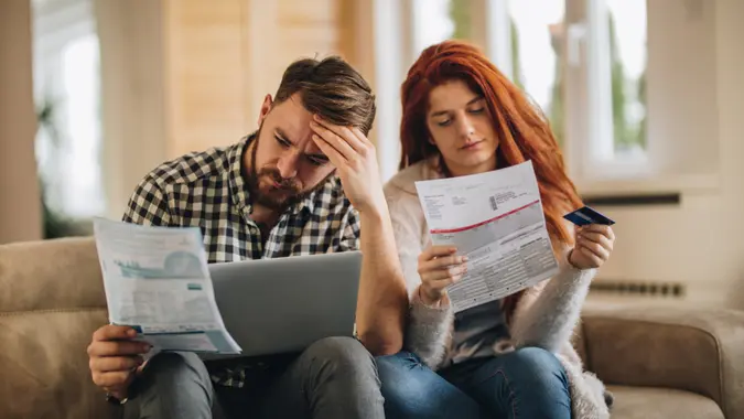 A worried couple is frustrated while having to pay bills over the internet.
