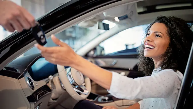 Car dealer is giving key for a new car to a woman.