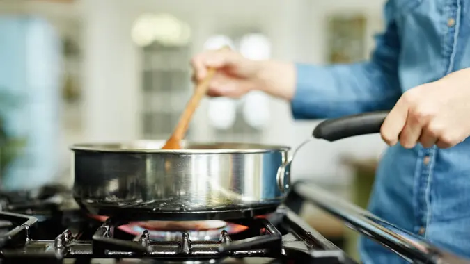 Close-up of woman cooking food in frying pan stock photo
