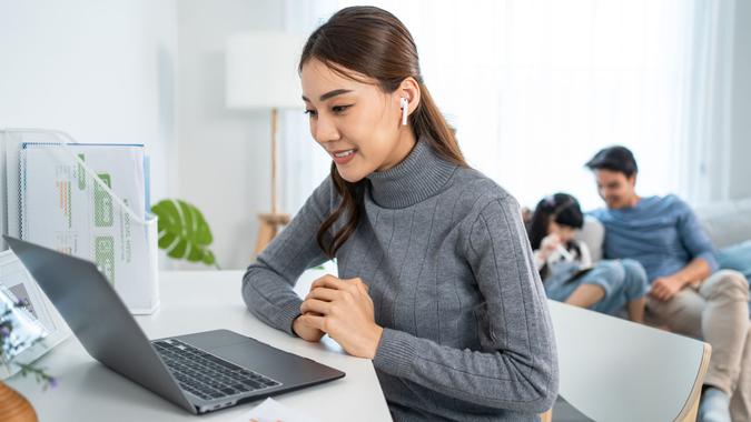 Asian businesswoman mother sit on table in living room, work from home.