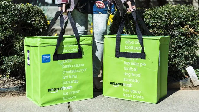 Amazon fresh insulated grocery delivery bag picked up by woman on front porch closeup stock photo