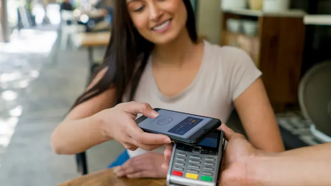 Femme dans un restaurant effectuant un paiement sans contact avec son téléphone portable photo stock