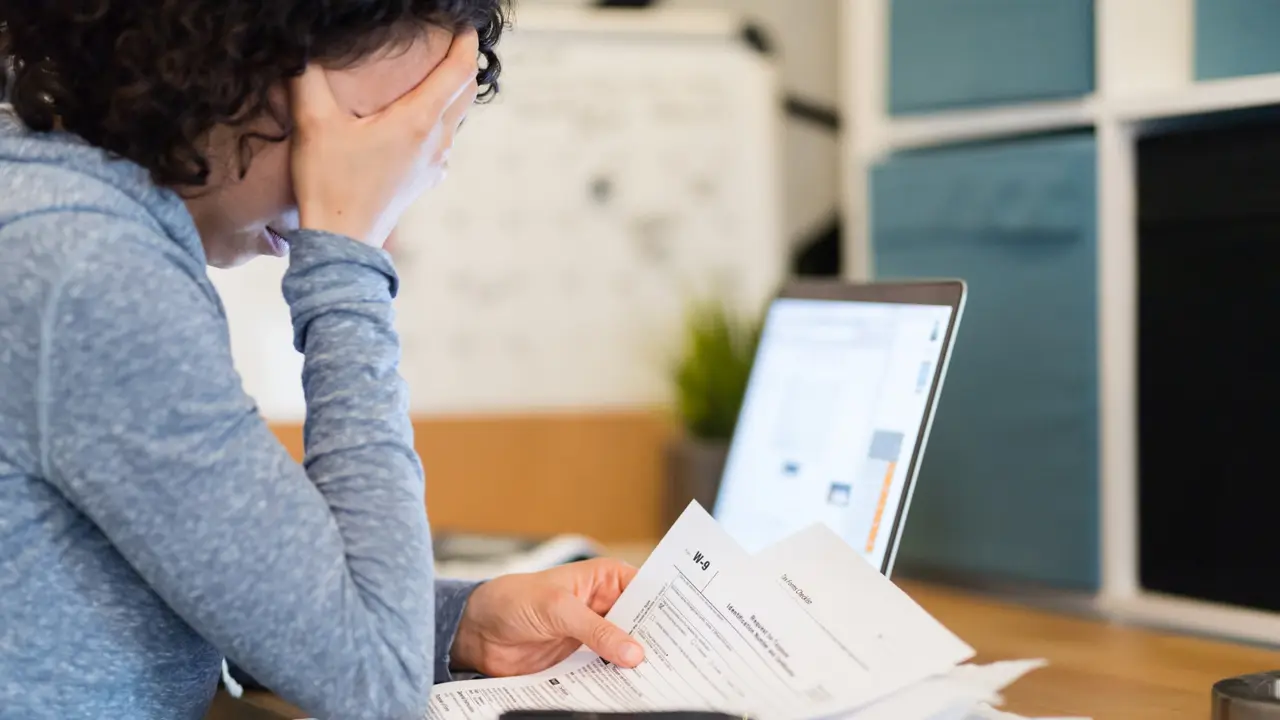 A young woman sits at a desk late at night and tries to work on her taxes.